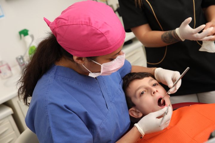 Una piccola paziente durante la visita, con l'odontoiatra e l'assistente